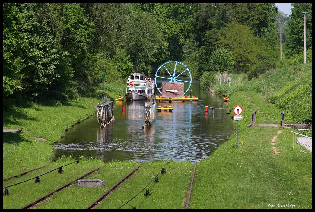 Oberlandkanal bei Buczyniec am 22.05.2012: Der Oberlandkanal in Polen ist heute  eine viel besuchte touristische Attraktion; denn dort wird man als Passagier auf dem Schiff mittels einer Standseilbahn über fünf Berge gezogen. Eine dieser Bergpassagen befindet sich bei Buczyniec. Am 22.05.2012 hielt ich eine solche Überfahrt im Bild fest: Gerade fährt das Schiff, die MARABU, aus Richtung Elblag kommend an der unteren Seilvorrichtung vorbei und steuert auf den noch im Wasser stehenden Rollwagen zu.