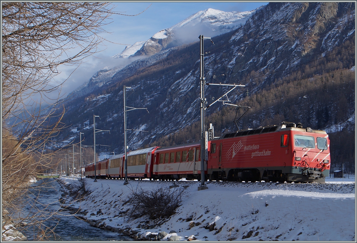 Obwohl die  Kometen  den Verkehr dominieren, sind von den schätzungsweise sieben Umläufen Zermatt nach Visp bzw. Fiesch mindestens zwei durch HGe 4/4 Pendelzüge abgedeckt, welche mit ihrem Glacier Express-Wagen einen zusätzlichen Komfort bieten.
hier verlässt der Zug 225 einen nur im Winter bedienten  Parkplatzhalt  bei Täsch.
28. Jan. 2015