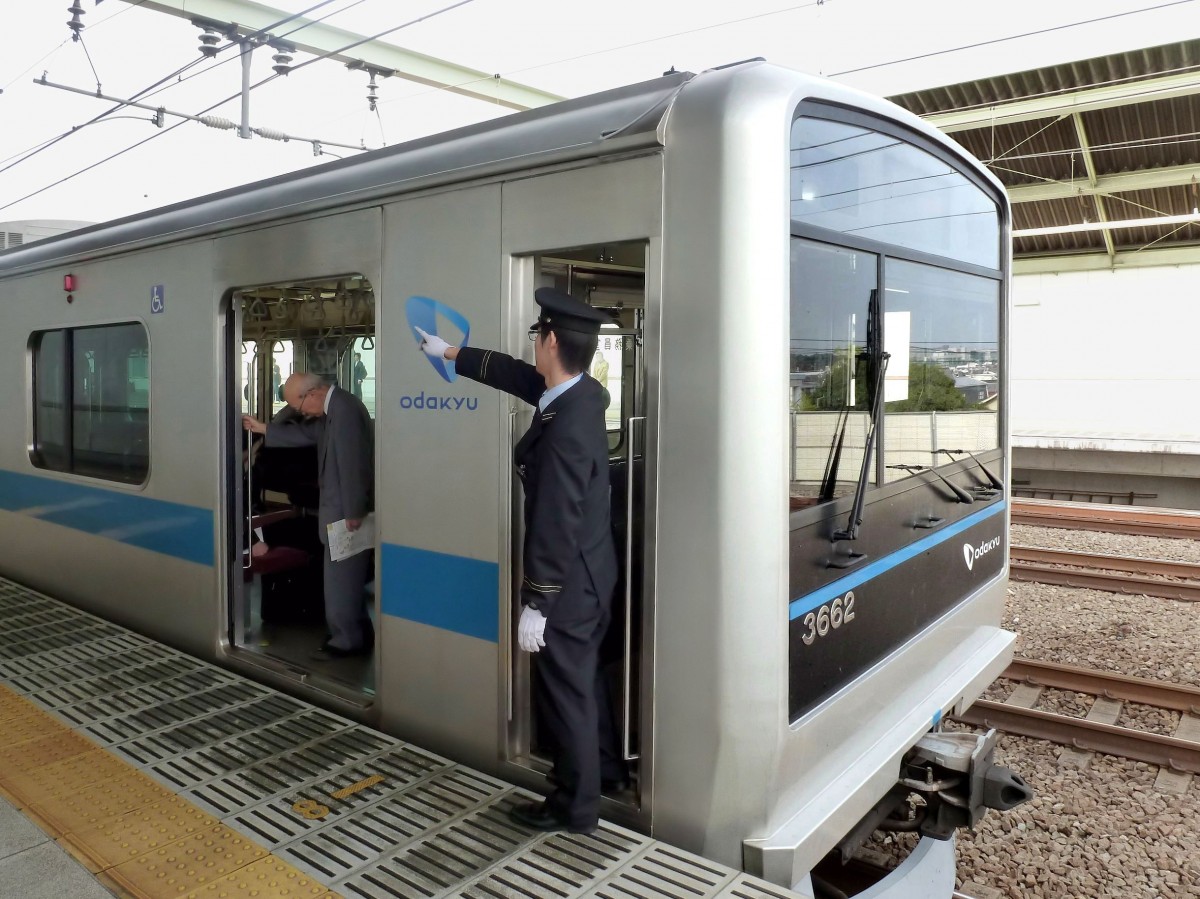 Odakyû Konzern, Serie 3000: Alle Fahrgäste sind eingestiegen, der Bahnsteigrand ist frei, die Türen können geschlossen werden. Der Schaffner im letzten Wagen des Zuges kontrolliert die Situation immer mit Fingerzeig und Ausrufen zur Selbstbestätigung. Zug 3662, Izumi Tamagawa, 12.Oktober 2011. 