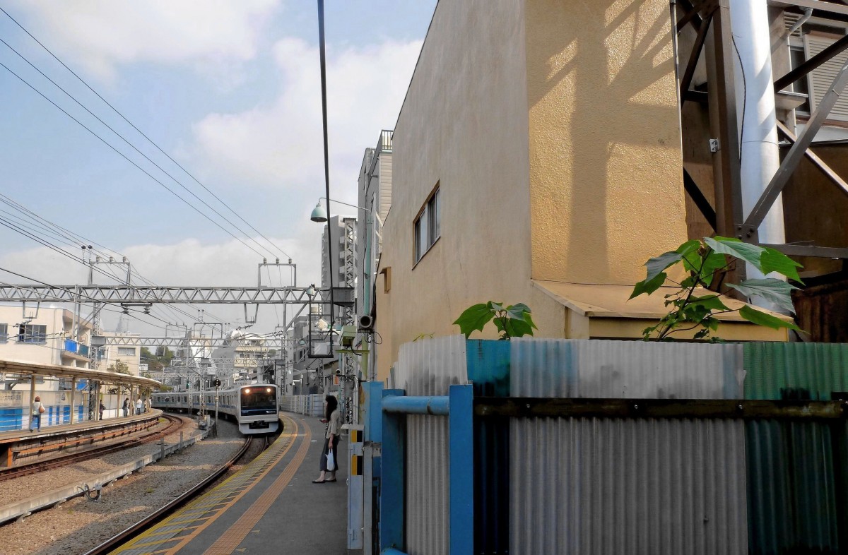 Odakyû Konzern, Serie 3000: Enge Häuserlandschaft im Innenbereich von Tokyo. Für ein paar Gewächse in ein paar Zentimeter Garten am Bahnhof Yoyogi Hachiman ist knapp genug Licht. Einfahrt des Zuges 3657, 12.Oktober 2011. 
