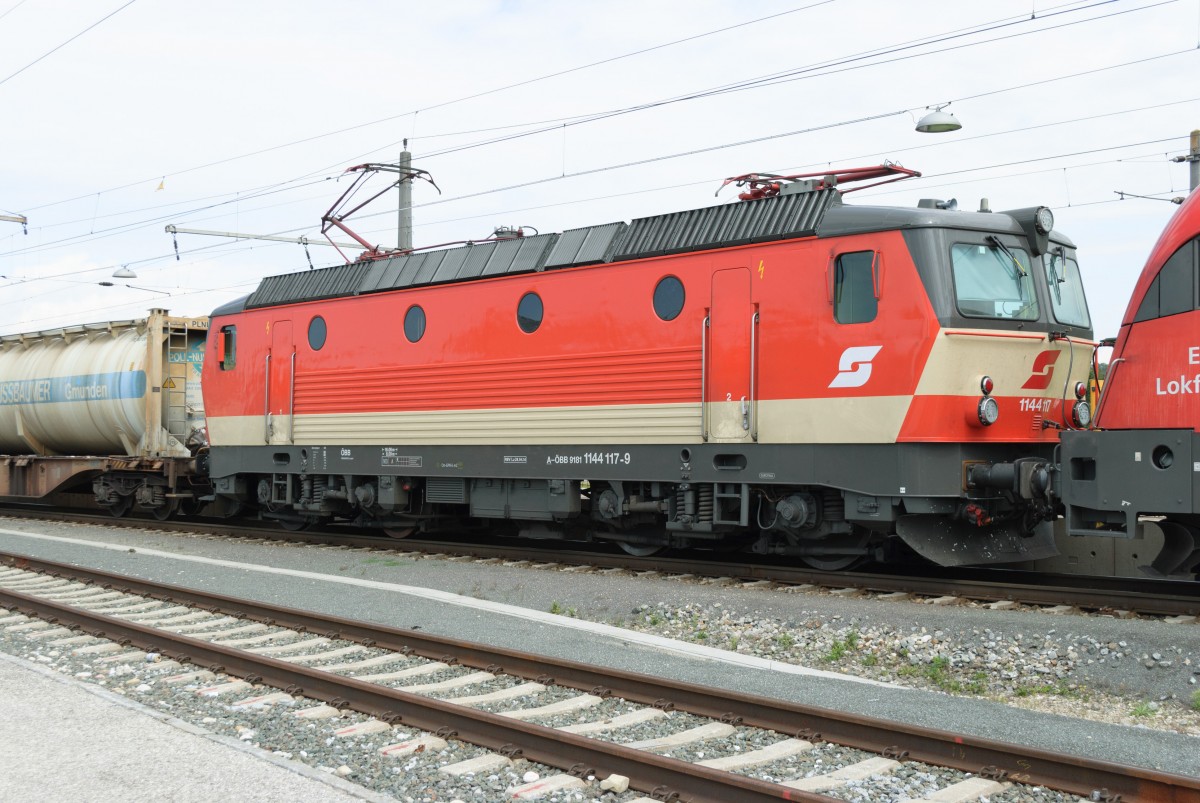ÖBB 1144 117-9 in alter  Schachbrett -Lackierung mit einer 1116 260-1 als Vorspann an einem Güterzug im Bahnhof Nettingsdorf.