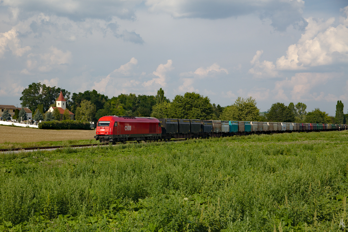 ÖBB 2016 098 mit einem umgeleiteten Güterzug auf der Pulkautalbahn in Fahrtrichtung Zellerndorf. Im Hintergrund die Kirche von Pfaffendorf. (10.08.2020)