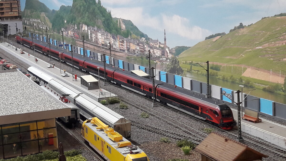 ÖBB Tage in Harrstadt, ein Railjet in Italienausführung wartet auf seine Abfahrt. Sicht von der Ostseite aus. Railjet ist eine Marke der Fernverkehrszüge in Österreich. Baujahr ab 2008, Züge gebaut von Siemens Mobility. Es werden gefahren immer 7teilige Einheiten, jedoch auch schon mal als Doppeleinheiten. Das Modell zeigt eine 7teilge Einheit. Lok von Piko und die kpl. Wageneinheit von Roco, siehe Einzelvorstellungen