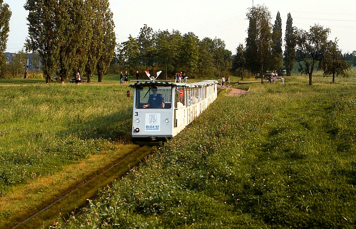 Ökologisch korrekt wurde ein Teil des Bundesgartenschaugeländes in Düsseldorf der Natur überlassen, diesen Teil passiert Lok Nr. 3 mit einem Zug im Sommer 1987. Kurzzeitig gab es Überlegungen, die Ausstellungsbahn auch über das Ende der Bundesgartenschau hinaus zu betreiben, diese Idee scheiterte jedoch an Anwohnerprotesten.