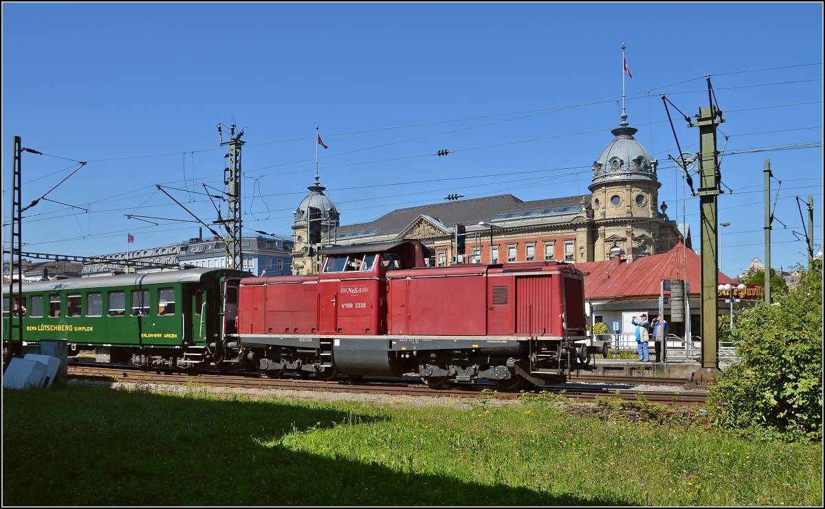 Oldiestunden im Grenzbahnhof. 

Der Sonderzug Basel-Augsburg mit V100 2335 vor dem mächtigen Gebäude der ehemaligen Oberpostdirektion. Juni 2014.