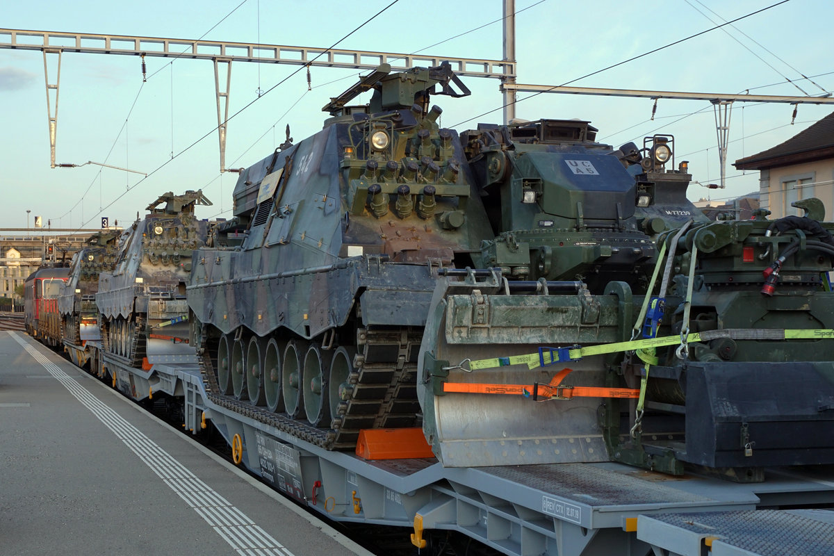 Panzerzug der Pz S 21 im Bahnhof Delémont am frühen Morgen.
Am 16. und 17. April 2020 wurden die Fahrzeuge der Pz Sap Kp 21/5 mit einem Zug von Thun Güterbahnhof nach Bure-Casernes transportiert. Für die Strecke Thun - Biel Rangierbahnhof stand die Re 420 329-5 im Einsatz. 
Nach der Übernachtung im RB Biel wurde für die Weiterfahrt bis Bure-Casernes die stärkere Re 620 007-5  WATTWIL  vorgespannt.
Dieser Zug hatte Biel noch während der Dunkelheit um 06:00h verlassen. 
Die Aufnahmen sind bei Gsteig, in Delémont und Glovelier entstanden.
Transportiert wurden:
4  G Pz Kodiak

5  BPz Büffel

1  Sap Pz 63/05

1  Kdo Pz 63/07 (Fleckenanstrich)

4  Sap Pz 63/05

1  Kdo Pz 63/07 (Fleckenanstrich)

3  Sap Pz 63/05

1  Kdo Pz 63/07 (Fleckenanstrich)

Foto: Walter Ruetsch