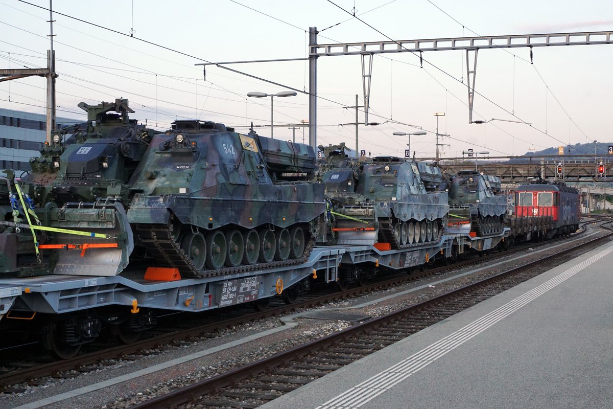 Panzerzug der Pz S 21 im Bahnhof Delémont am frühen Morgen.
Am 16. und 17. April 2020 wurden die Fahrzeuge der Pz Sap Kp 21/5 mit einem Zug von Thun Güterbahnhof nach Bure-Casernes transportiert. Für die Strecke Thun - Biel Rangierbahnhof stand die Re 420 329-5 im Einsatz. 
Nach der Übernachtung im RB Biel wurde für die Weiterfahrt bis Bure-Casernes die stärkere Re 620 007-5  WATTWIL  vorgespannt.
Dieser Zug hatte Biel noch während der Dunkelheit um 06:00h verlassen. 
Die Aufnahmen sind bei Gsteig, in Delémont und Glovelier entstanden.
Transportiert wurden:
4  G Pz Kodiak

5  BPz Büffel

1  Sap Pz 63/05

1  Kdo Pz 63/07 (Fleckenanstrich)

4  Sap Pz 63/05

1  Kdo Pz 63/07 (Fleckenanstrich)

3  Sap Pz 63/05

1  Kdo Pz 63/07 (Fleckenanstrich)

Foto: Walter Ruetsch