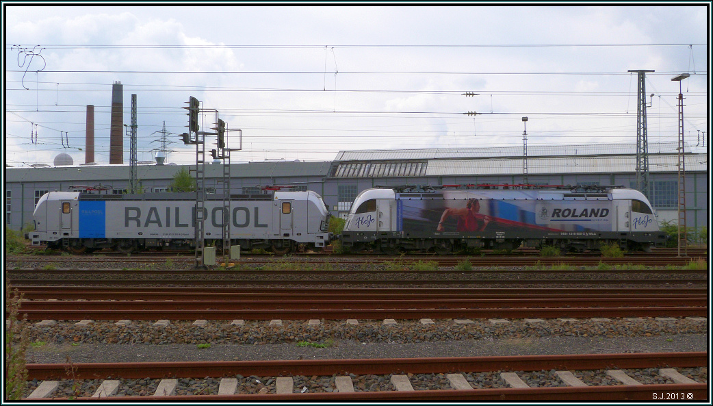 Parkplatz International! Heute zu Gast: 2 Loks der Wiener Lokalbahnen Cargo.
Hier zu sehen die Taurus 1216 (955-8) im Roland Speditionsdesign,sowie die neue 
Siemens Vectron Lok angemietet von Railpool. Bildlich festgehalten am Bahnhof in Herzogenrath,(Kr.Aachen.), im September 2013.