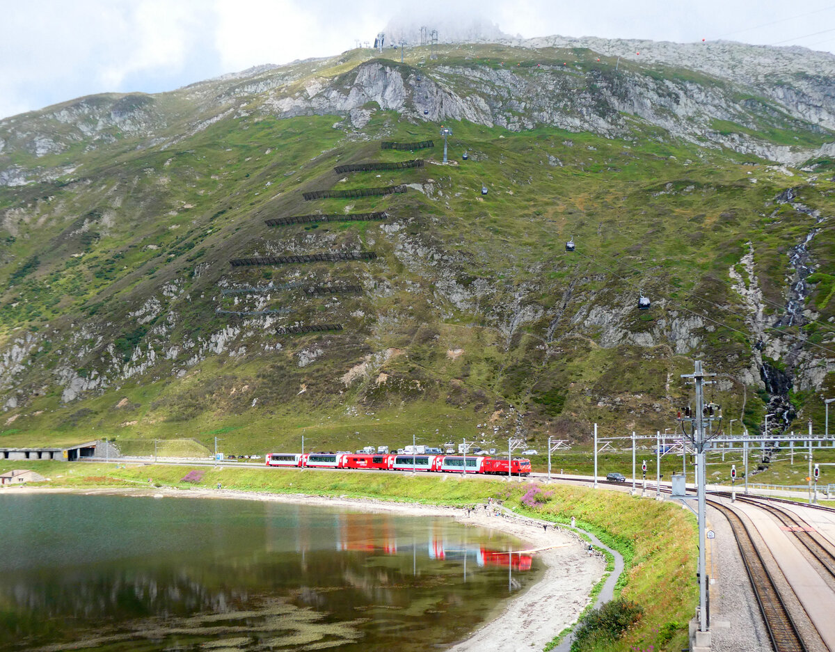 Perfekt getroffen: der Glacier-Express von Zermatt nach St. Moritz f�hrt in einem 'Wolkenloch' bzw an der Sonne in die Station Oberalppass (2033 m�M) ein. Das Foto wurde vom Parkplatz oberhalb des Bahnhofs gemacht. Oberalppass, 7.8.2026