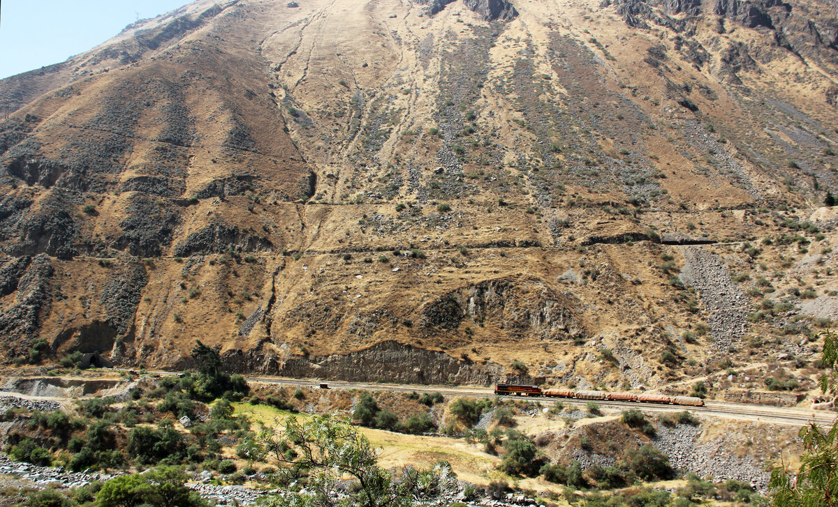 Perfekte Sicht auf einen interessanten Streckenabschnitt der Zentralbahn in Peru zwischen Lima und Matucana von der Strasse aus: entweder werden an dieser Stelle Kehrtunnels befahren oder es handelt sich um eine so genannte Zick-Zack-Strecke. Auf der untersten Ebene steht ein bergw�rts fahrender G�terzug mit f�nf Wagen. Die mittlere Ebene verl�uft von links nach rechts ansteigend �ber dem G�terzug. Dar�ber ist die oberste Trassee zu sehen, nur leicht nach links ansteigend. Oben ist noch ein Fusspfad zu sehen. Wir verbrachten einen Tag mit dem Auto zwecks Trainspotting an der Zentralbahnstrecke zwischen Lima (etwas �ber Meeresh�he) und Matucana (2389 m�M). Eine h�chst imposante Streckenf�hrung! Matucana, 1.8.2015