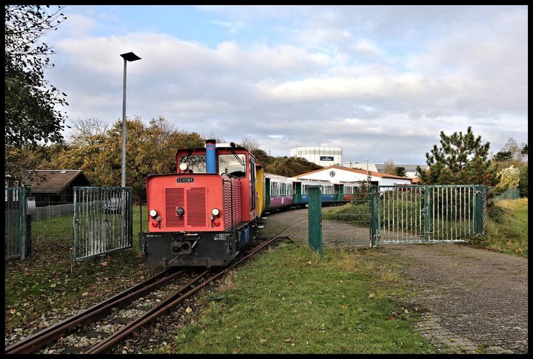 Personenzug Garnituren werden auf Borkum in einer besonderen separaten Wagenhalle unweit der Werkstatthalle abgestellt. Die Züge bestehen in der Regel aus zwei Teilen und werden dort zusammen rangiert und dann auf die vorbeiführende Bahnstrecke gezogen. Hier sehen wir Lok Aurich am 24.10.2022 um 09.55 Uhr bei der Ausfahrt eines solchen Zuges aus dem Gelände an der Wagen Remise auf die Bahnstrecke.