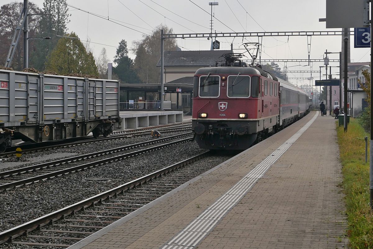 Plötzlich und unerwartet zieht Re 4/4 II 11304 einen unbekannten und vermutlich umgeleiteten Nachtzug mit Sitz-, Liege- und Schlafwagen der ÖBB, HŽPP und SBB am 10.11.2021 durch den Bahnhof von Bürglen (TG)