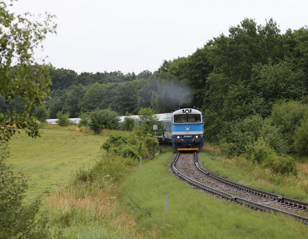 Pro Tag verkehrt ein Intercity Zugpaar zwischen Prag und Krummau via Budweis. Auf der eingleisigen Bergstrecke zwischen Budweis und Krummau ist hier am 9.8.2023 um 11.36 Uhr die Taucherbrille 754062-8 nahe Vrabce mit dem Jizni Express IC 533 nach Krummau unterwegs. 