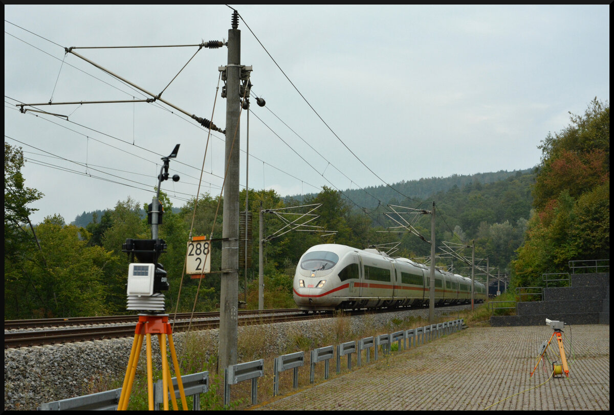 Projekt „300 km/h auf alten Schnellfahrstrecken“ - Testfahrt Nr. 3: ICE 406 010/510  Frankfurt am Main  (Tz 4610) rast am 04.09.2024 mit 310 km/h aus dem 2159 Meter langen Sinnberg-Tunnel auf der SFS Fulda - Würzburg der unterfränkischen Residenzstadt entgegen. Auf dem Rettungsplatz Sinnberg-Tunnel Portal Süd bei Rieneck sind eine Wetterstation (links) zur Aufzeichnung der meteorologischen Bedingungen und eine Zeilenkamera (rechts) zur Oberleitungsbeobachtung aufgebaut.