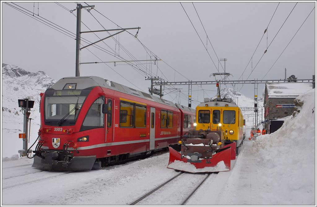 R1621 mit ABe 8/12 3502 überholt in Ospizio Bernina einen Dienstzug bestehend aus Spurpflug Xk9143, Xe 4/4 23201 und einem Flachwagen, die mit Schneeräumung beschäftigt sind. (14.01.2016)