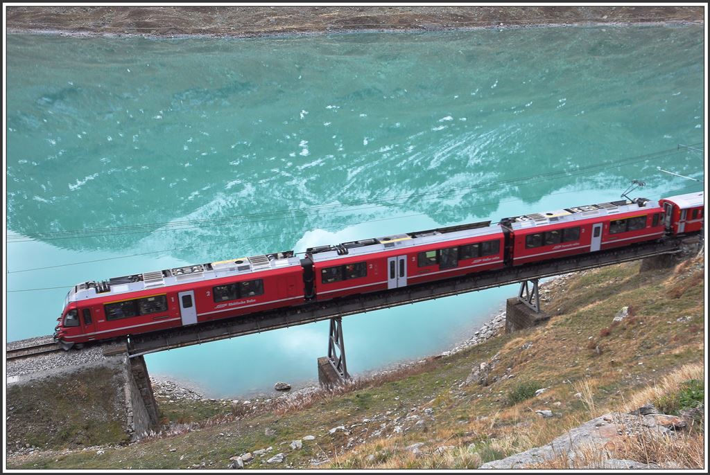 R1633 mit ABe 8/12 3508 auf der Brücke am See unmittelbar hinter der Station Ospizio Bernina auf 2253m ü/M.. Im Lago Bianco spiegelt sich an diesem Morgen der Cambrenagletscher. (08.10.2015)