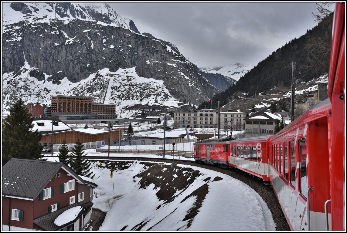 R823 mit Deh 4/4 21 fährt in Andermatt ein. im Hintergrund links die Gotthard Residences und Radisson Blue Hotel und rechts über der Lok die Militärkaserne. (10.04.2019)