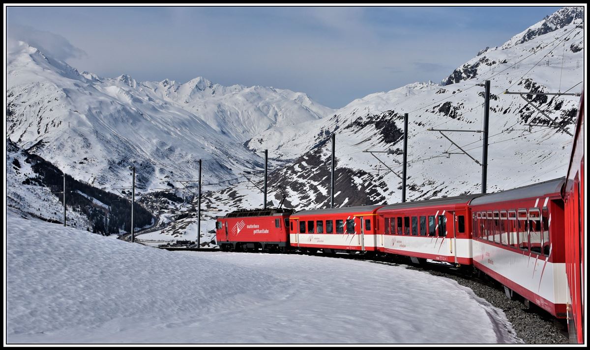 R823 mit der HGe 4/4 II 107 nach Andermatt unterhalb von Nätschen. Im Hintergrund ist das Urserental mit Hospental und Realp zu sehen. (16.04.2019)