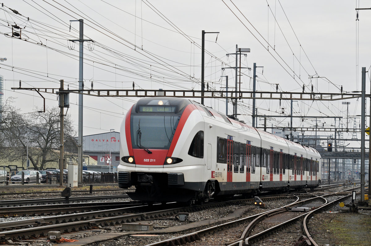 RABe 522 211, auf der S3, verlässt den Bahnhof Pratteln. Das abzweigende Gleis führt auf eine Strasse und in ein Industriegebiet, von wo aus auch diese Aufnahme am 07.02.2017 entstand.