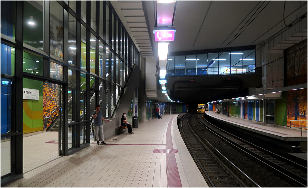 Räumlich großzügig -

Im Gegensatz zu Frankfurt ging man in Stuttgart schon früh dazu über, bei den unterirdischen Stationen die Zwischenebene mit dem Bahnsteigbereich in Forum einer Halle offen zu verbinden. Auch wurde auf Mittelstützen verzichtet, wie schon bei den ersten U-Stationen, die noch nicht in dieser Hallenform gebaut wurden. Durch die erhöhten Anforderungen an den Brandschutz mussten jetzt aber Glaswände eingefügt werden, um die die Ausgänge möglichst lange Rauchfrei zu halten. Ein Teil der einstiegen Großzügigkeit ging dadurch verloren.

Hier die 1972 eröffnete Station am 'Neckartor', unter der Straßenkreuzung die aufgrund anderer Gründe negativ bundesweit bekannt wurde.

20.07.2021 (M)
