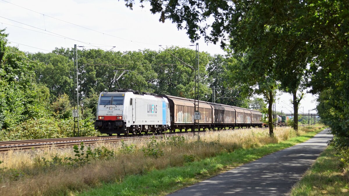 Railpool 186 452, vermietet an Lineas, mit Schiebewandwagen und einigen mit Containern beladenen Wagen in Richtung Bremen (bei Lembruch, 28.07.2022).