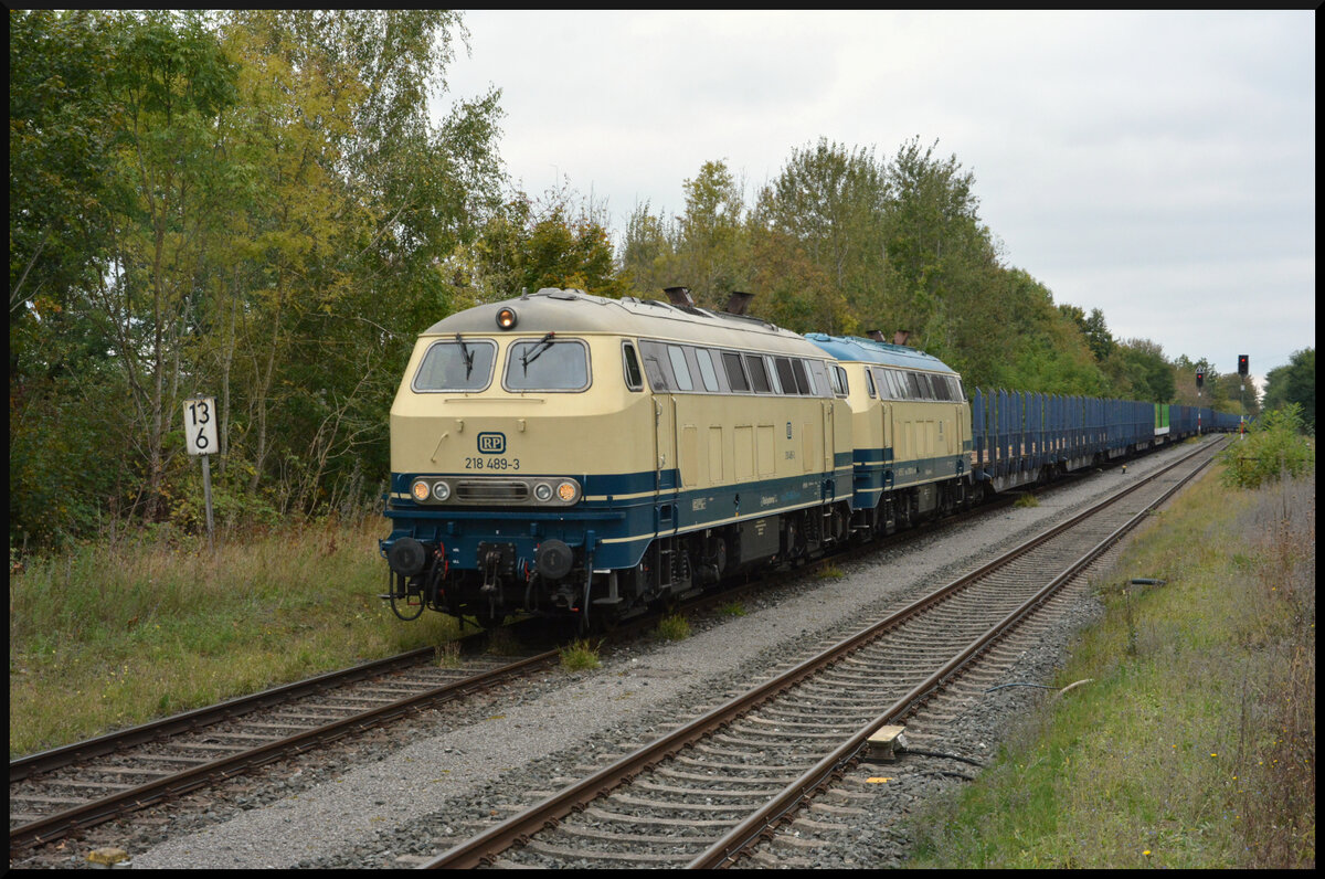Railsystems RP 218 489-3 und 381-2 rollen am 06.10.2024 mit ihren Rungenwagen langsam in Bahnhof Ebenhausen/Unterfranken, um die Kreuzung mit einem Regionalexpress abzuwarten.