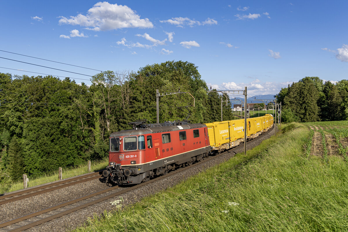 Re 420 261-0 ist mit dem Postzug aus dem Tessin unterwegs in Richtung Mittelland, aufgenommen bei Mühlau AG am 10.06.2024.