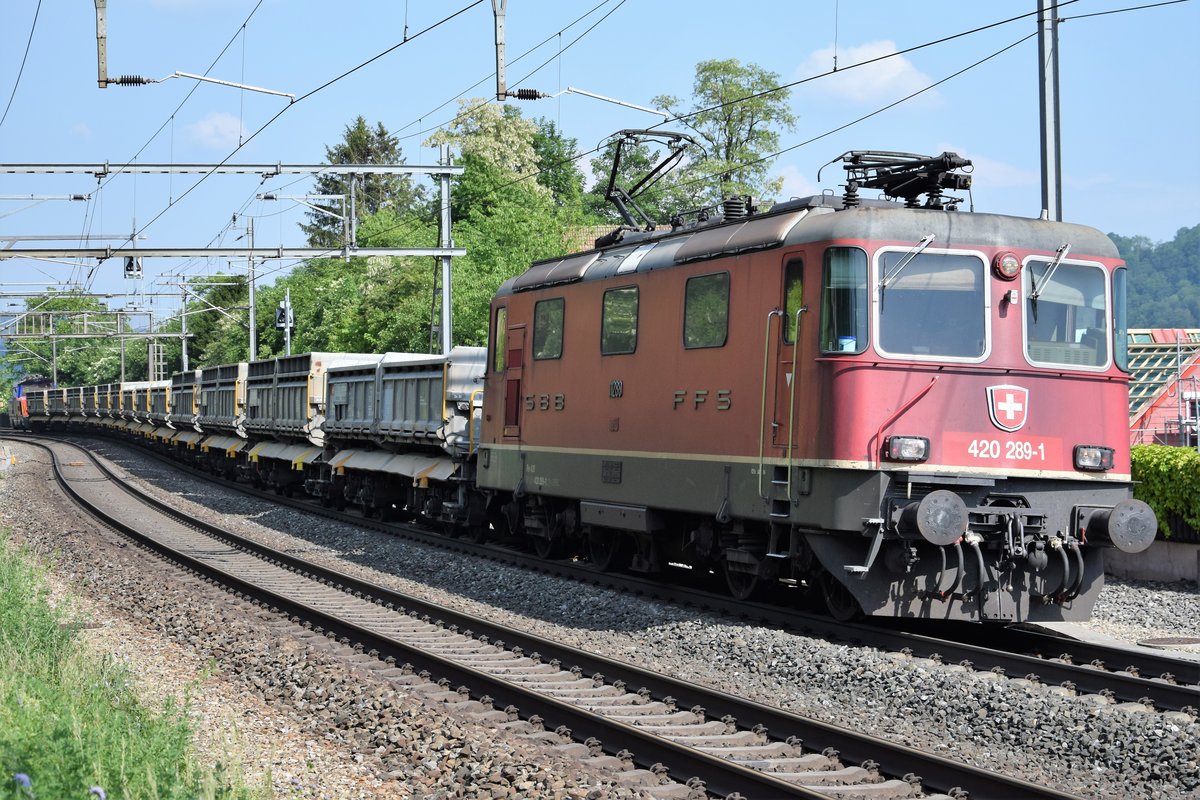 Re 420 289-1 mit einem Aushubzug unterwegs auf der Bözberg Südrampe am 18.05.2018, festgehalten bei der Durchfahrt in Villnachern. Am anderen Ende des Zuges läuft die Eem 923 018-6 mit.