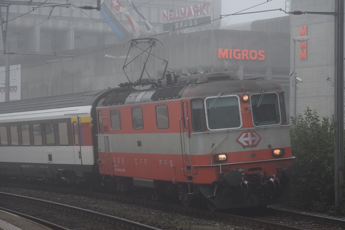 Re 4/4 II 11108  Swiss Express  zieht am 14.10.2017 in Brugg den Interregio nach Zürich HB aus dem Nebel in Richtung Baden.