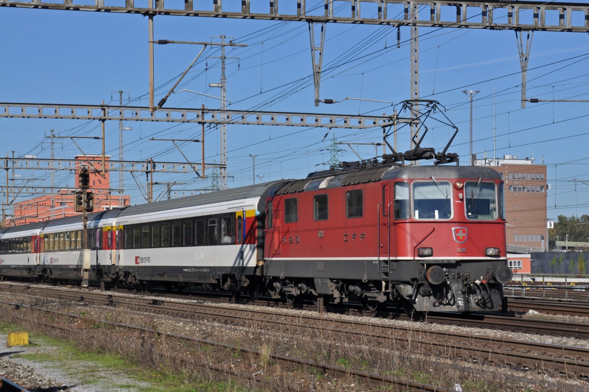 Re 4/4 II 11128 durchfährt den Bahnhof Muttenz. Die Aufnahme stammt vom 18.10.2014.
