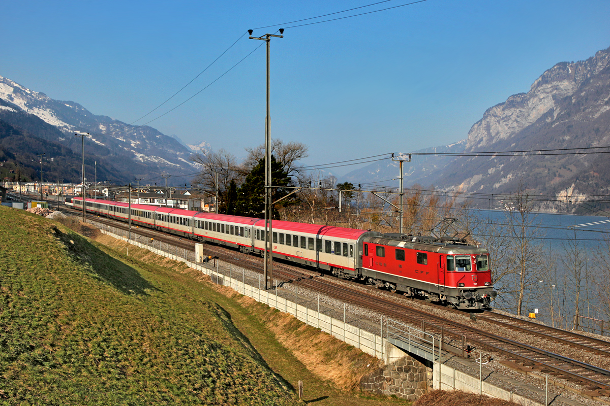 Re 4/4 II 11129 mit dem EC von Zürich HB nach Graz braust bei Unterterzen vorüber.Bild vom 12.3.2015
