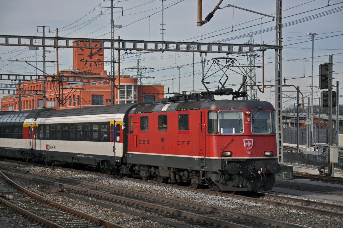 Re 4/4 II 11150 durchfährt den Bahnhof Muttenz. Die Aufnahme stammt vom 22.12.2014.