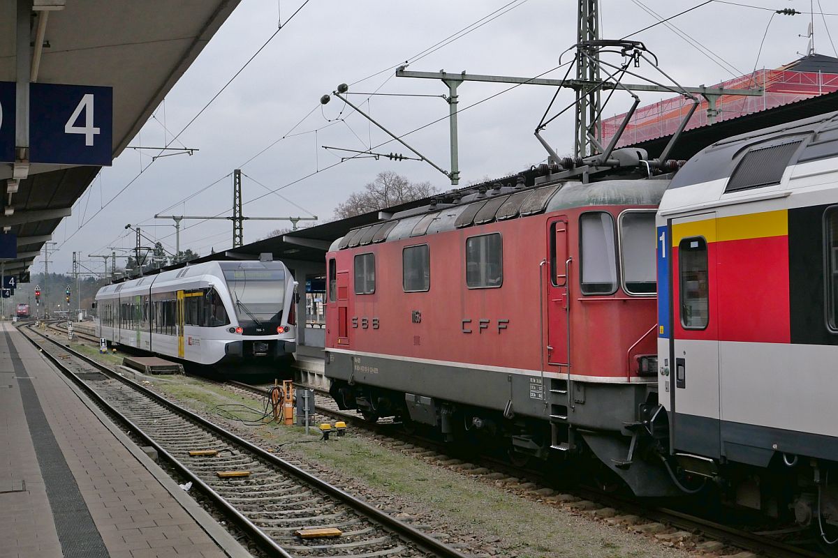 Re 4/4 II 11153 zieht mit geringer Geschwindigkeit die Wagen des IC 487, Singen (Hohentwiel) - Zürich, zur Bereitstellung an den Bahnsteig, der noch teilweise von einer Regionalbahn nach Schaffhausen belegt ist. Singen, 28.01.2023