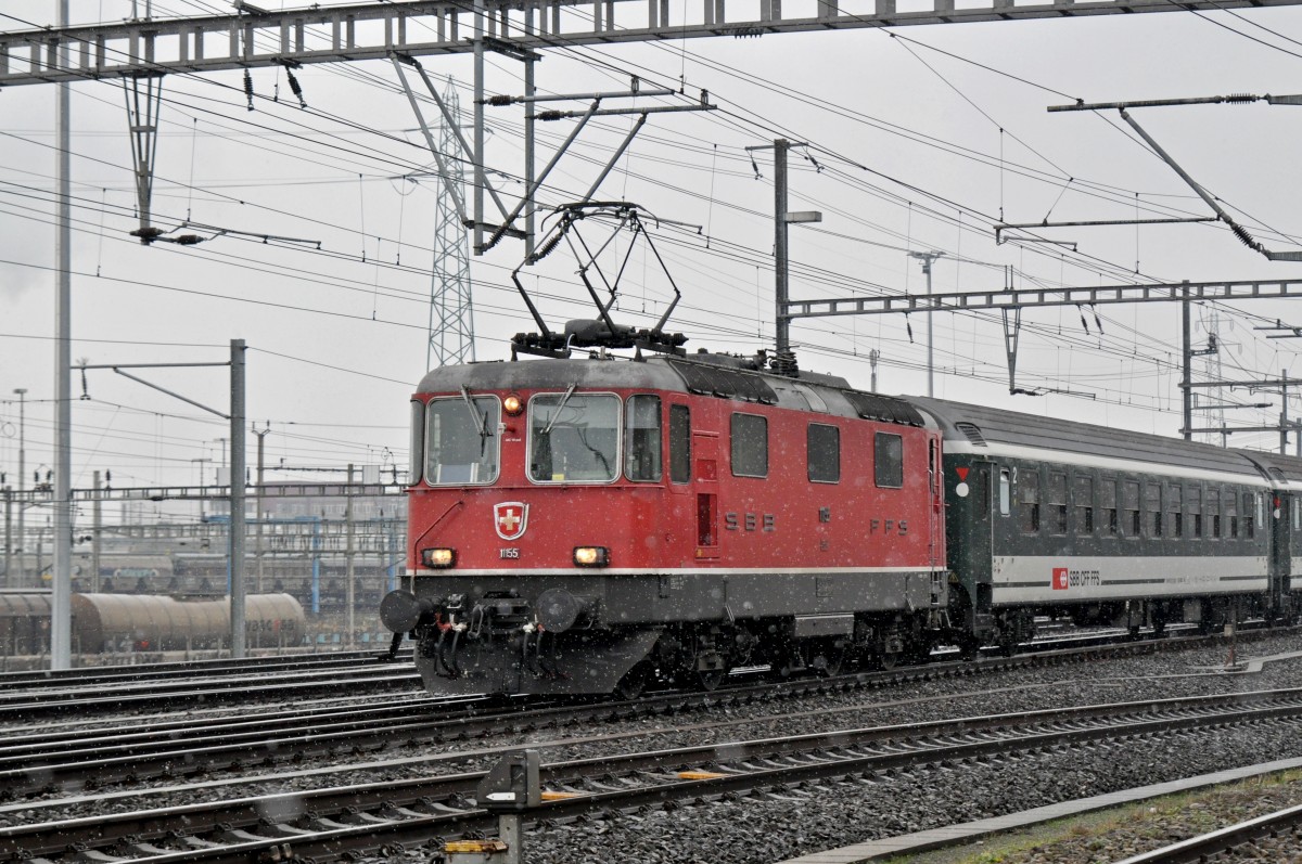 Re 4/4 II 11155 durchfährt bei leichtem Schneefall den Bahnhof Muttenz. Die Aufnahme stammt vom 26.01.2015.