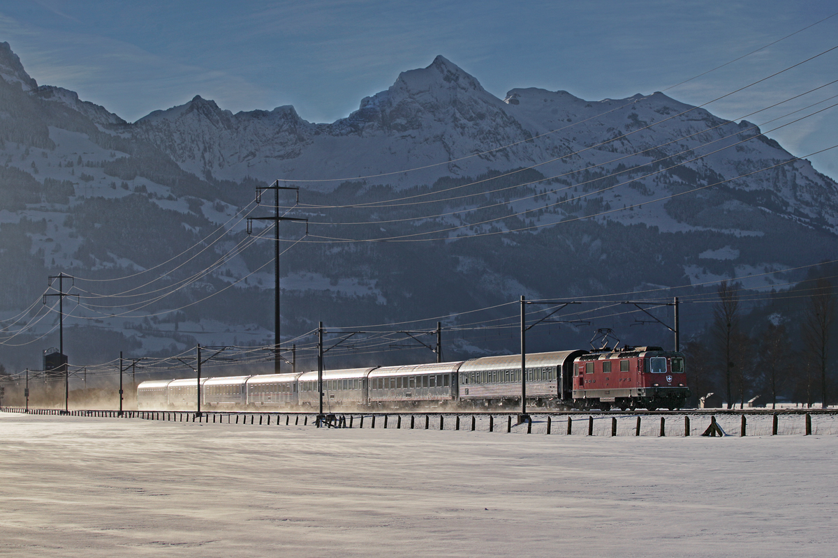 Re 4/4 II 11155 mit dem ECN aus Beograd nach Zürich HB fährt bei starkem Biswind bei Bilten vorbei.Bild vom 10.2.2015