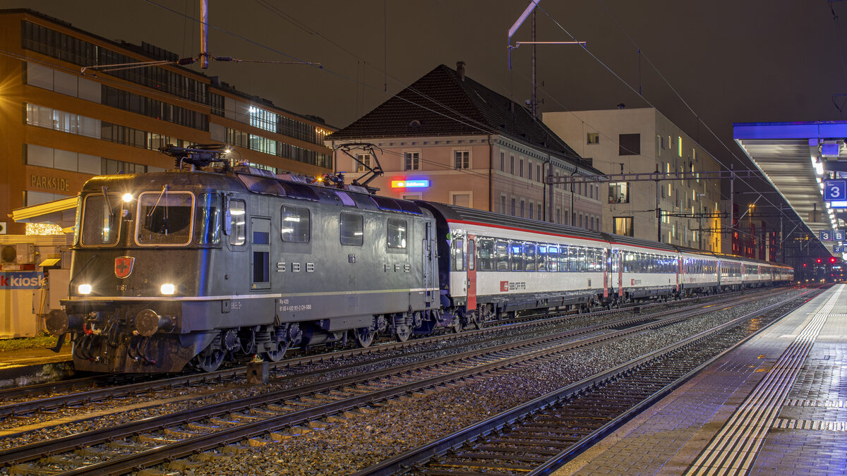 Re 4/4 II 11161 mit einem Leermaterial-Zug, aufgenommen beim Halt in Schlieren am Abend des 28.11.2021.
