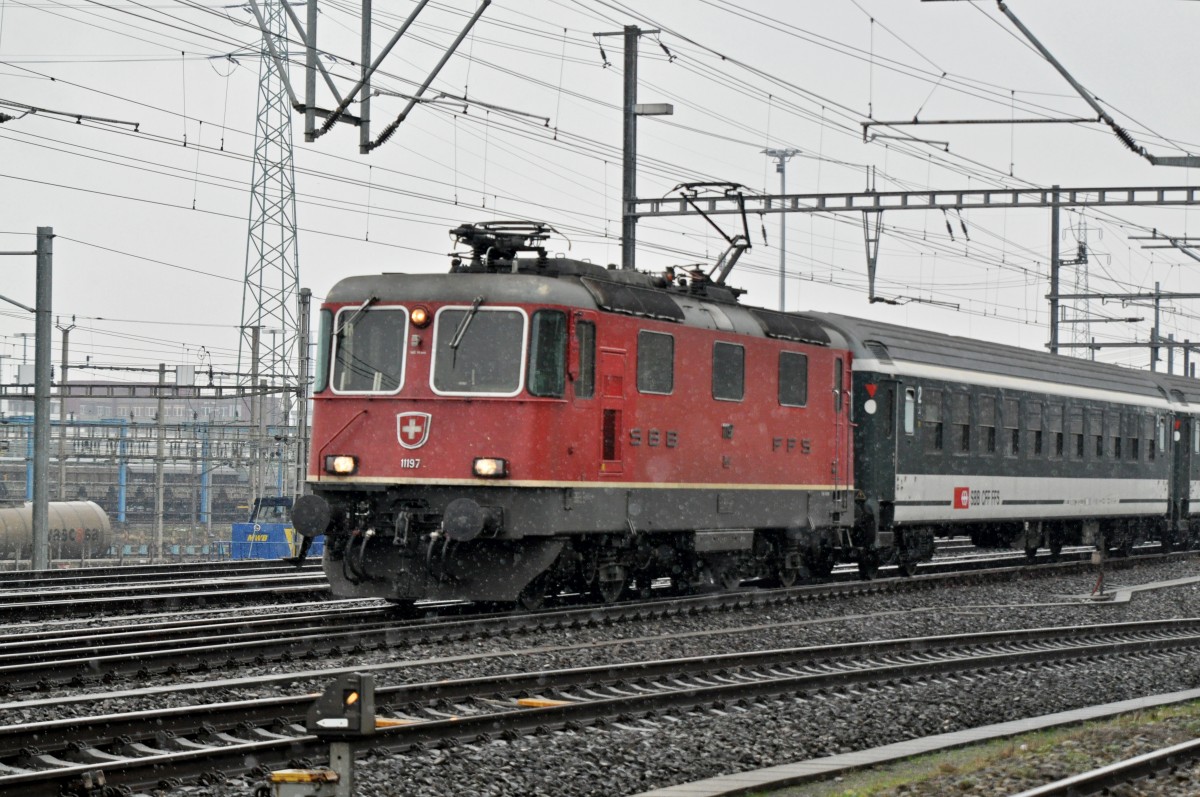 Re 4/4 II 11197 durchfährt bei leichtem Schneefall den Bahnhof Muttenz. Die Aufnahme stammt vom 26.01.2015.