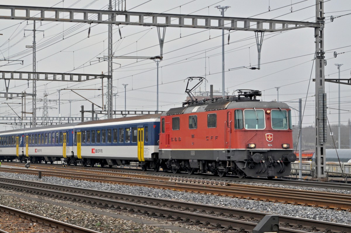 Re 4/4 II 11214 durchfährt den Bahnhof Muttenz. Die Aufnahme stammt vom 24.01.2015.