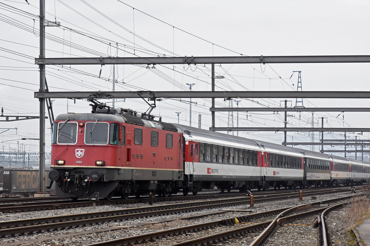 Re 4/4 II 11302 durchfährt den Bahnhof Muttenz. Die Aufnahme stammt vom 02.03.2019.