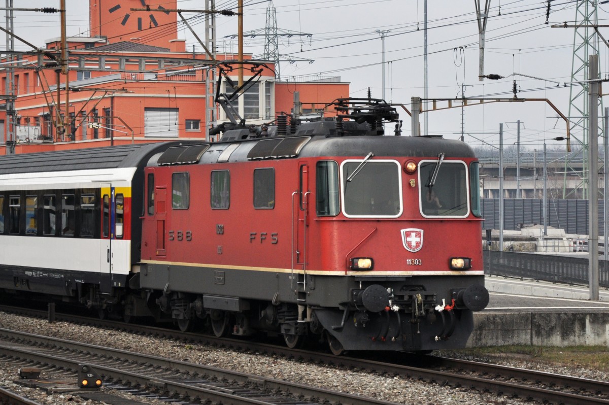 Re 4/4 II 11303 durchfährt den Bahnhof Muttenz. Die Aufnahme stammt vom 13.01.2014.