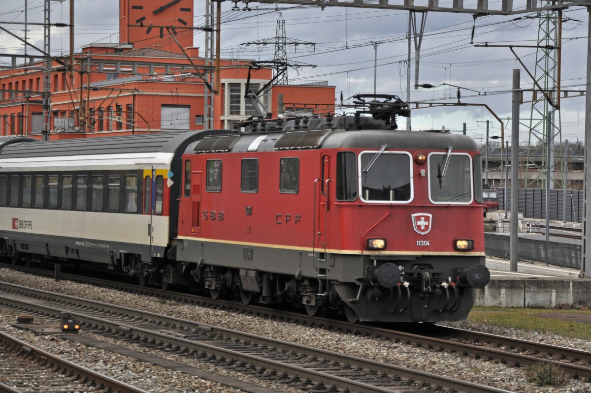 Re 4/4 II 11304 durchfährt den Bahnhof Muttenz. Die Aufnahme stammt vom 16.02.2014.