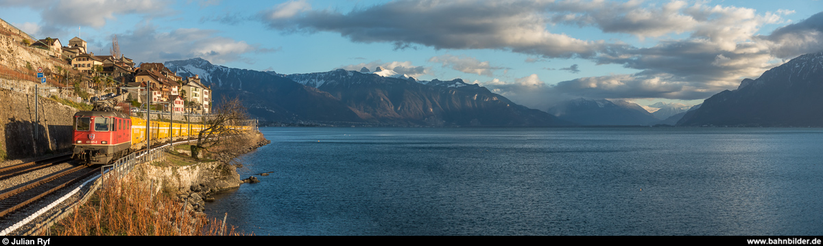 Re 4/4 II 11321 mit dem wegen eines Lokdefekts mehr als zweieinhalb Stunden verspäteten Postzug 50294 Brig - Daillens am 2. Januar 2019 bei St-Saphorin. Für den Fotografen ein Glücksfall - gab es so doch noch etwas Abwechslung zwischen den Personenzügen.<br>
Dieses Panoramabild ist auf <a href= https://www.flickr.com/photos/zettie94/46563444742/in/datetaken-public/ >Flickr</a> auch in grösserer Auflösung zu finden.