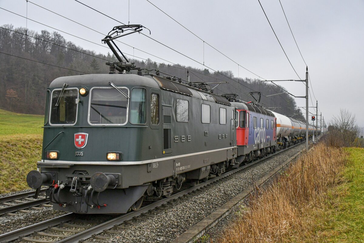 Re 4/4 II 11335 ist mit Re 6/6 11609  Uzwil  aus dem Tessin kommend nach Basel unterwegs, aufgenommen bei Villnachern AG am 15.12.2021.