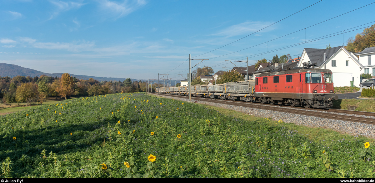 Re 4/4 III 11354 mit einem Aushubzug des neuen Bözbergtunnels von Schinznach Dorf nach Wildegg am 26. Oktober 2018 bei Holderbank. Da die Züge auf dem kurzen Laufweg auch noch die Fahrtrichtung ändern müssen, werden sie mit einer Re 4/4 II/III und einer Eem 923 im Sandwich bespannt, wobei die hintere Lok jeweils geschleppt wird.