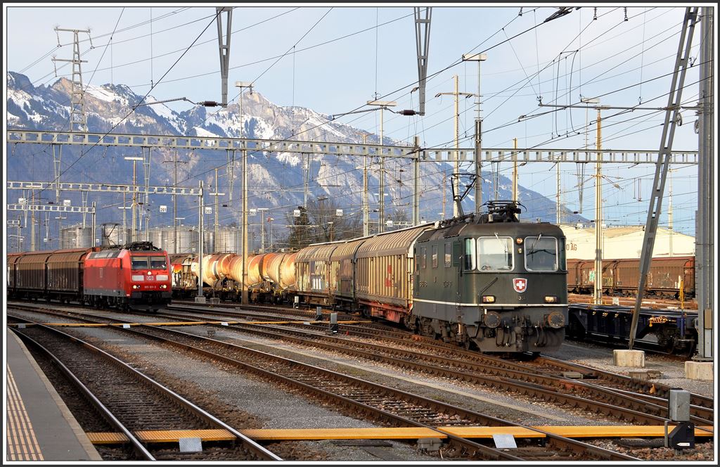 Re 4/4 III 11364 verlässt mit einem Güterzug Buchs SG Richtung Sargans. Daneben steht die 185 101-3 mit einem abfahrbereiten Red Bull Zug. Im Hintergrund grüsst der Hohe Kasten. (15.01.2015)