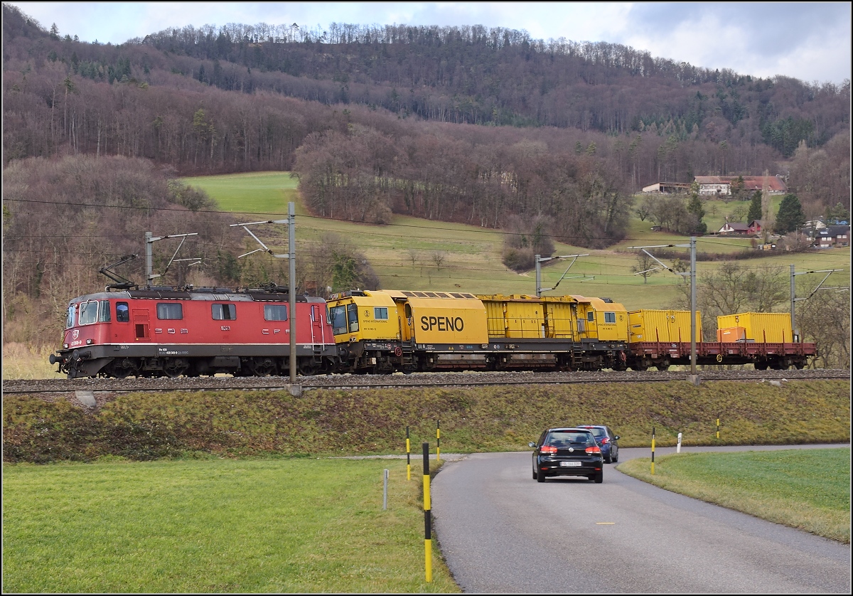 Re 4/4 III 11369 mit dem Spenoschienenschleifzug 99 85 9 127 110-8 CH-SPENO in Bckten. Hier darf mal das Servicefahrzeug statt der Lok unverdeckt ins Bild. Januar 2018.