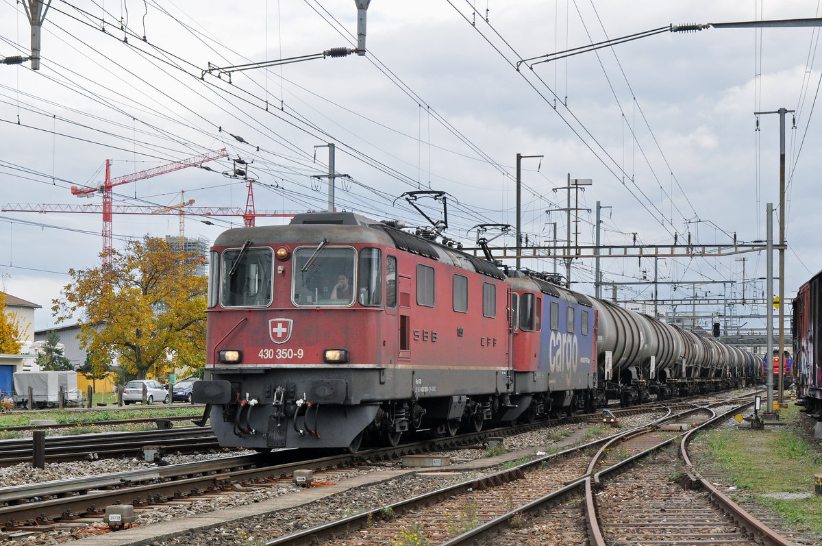 Re 4/4 III 430 350-9 (11350) und eine Re 421, durchfahren den Bahnhof Pratteln. Das abzweigende Gleis führt auf eine Strasse und in ein Industriegebiet, von wo aus auch diese Aufnahme am 20.10.2016 entstand. 