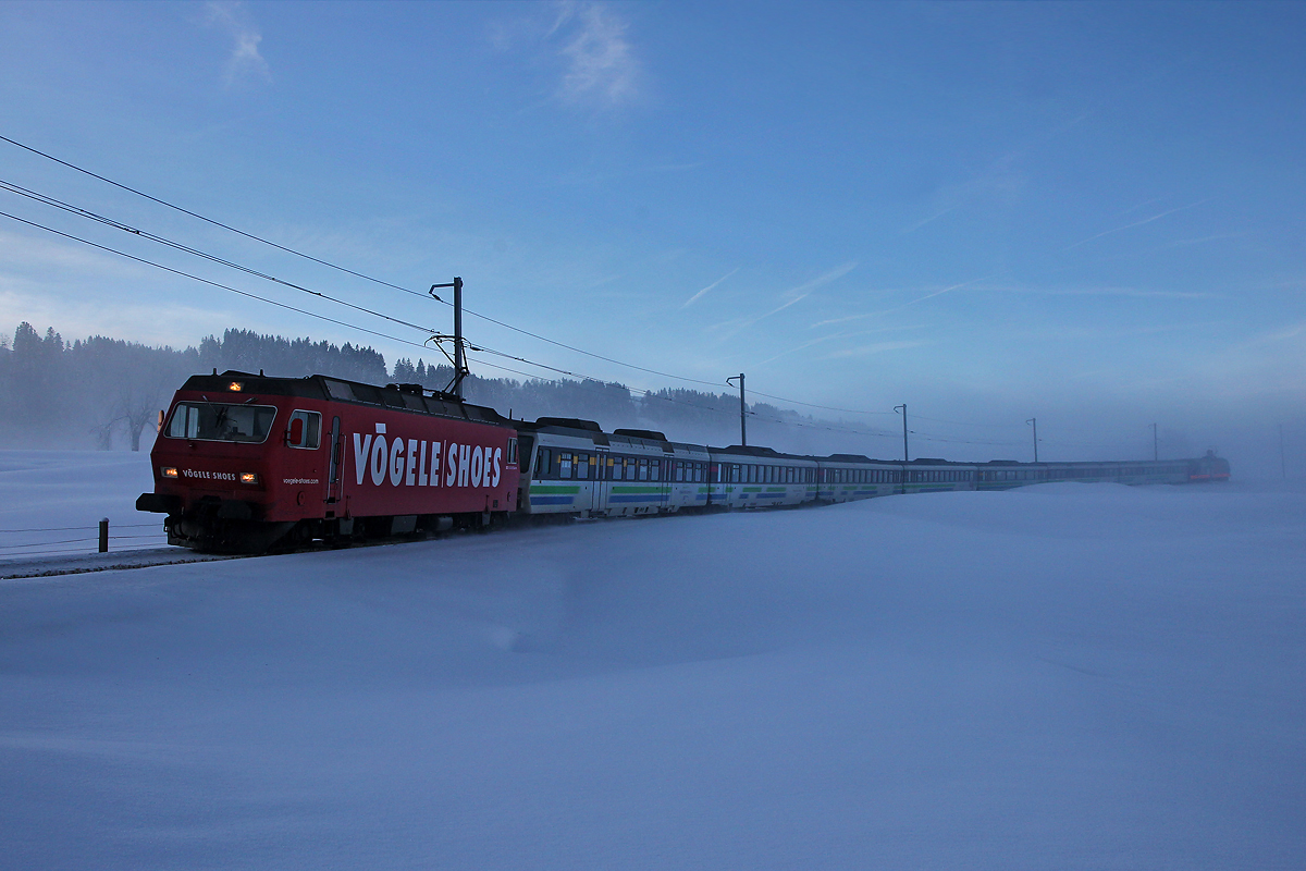 Re 456 094 als Zuglok mit der Schublok Re 456 092 tauchen mit dem Voralpenexpress aus eisigem Morgennebel auf.Bild aus Schwyzerbrugg,2.1.2015