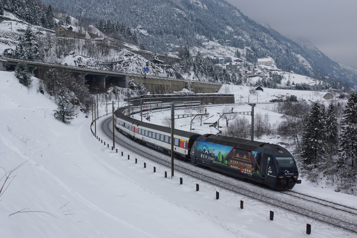 Re 460 023-5 mit Werbung für das 100-Jahr Jubiläum des Hauseigentümerverbandes Schweiz durchfährt am 07.02.2015 die Wattingerkurve unterhalb von Wassen.
