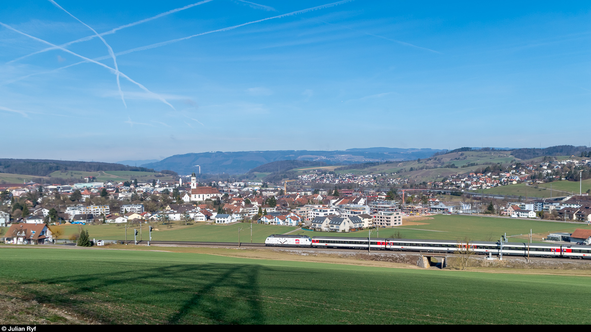 Re 460 044 mit Werbung für Mondaine fährt am 25. Februar 2017 mit einem IR Zürich - Basel bei Frick vorüber.